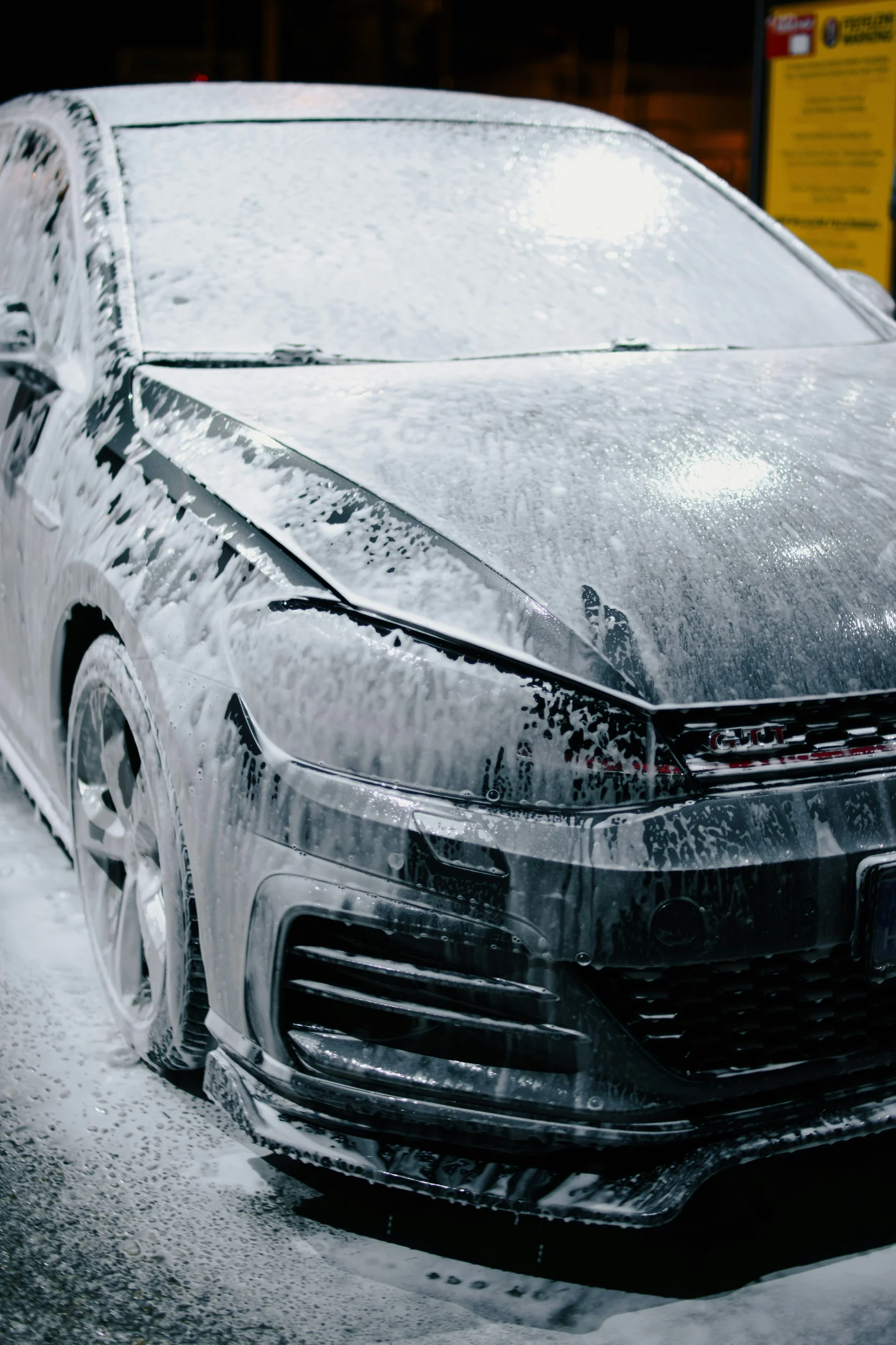 Volkswagen Golf GTI preto coberto de espuma durante uma lavagem